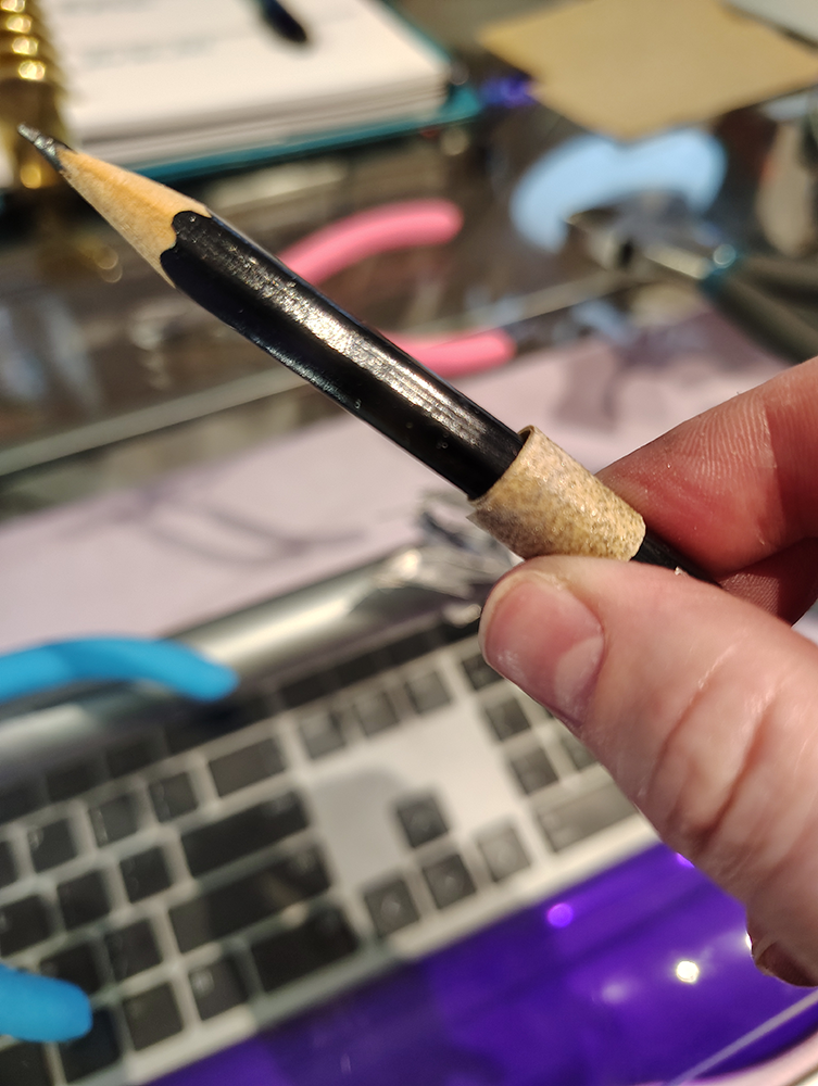 A strip of sandpaper wrapped around a pencil.
